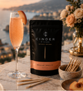 Bellini Spritz cocktail with Cinder Picks packaging on a scenic background