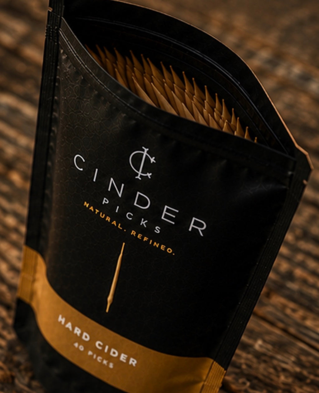 Cinder Picks packaging with brand logo on a wooden background