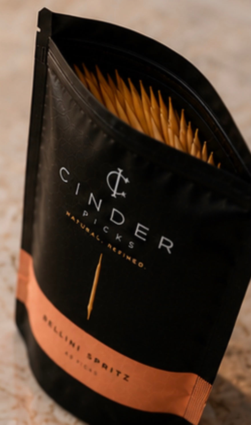 Black and peach coloured pouch of Cinder Picks with a textured background