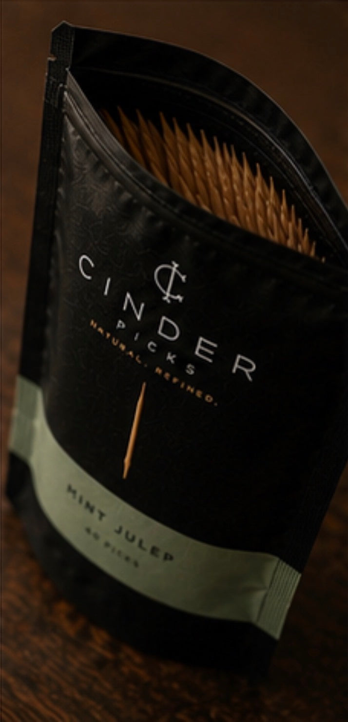 Packaged picks with 'Cinder Picks' branding on a wooden surface