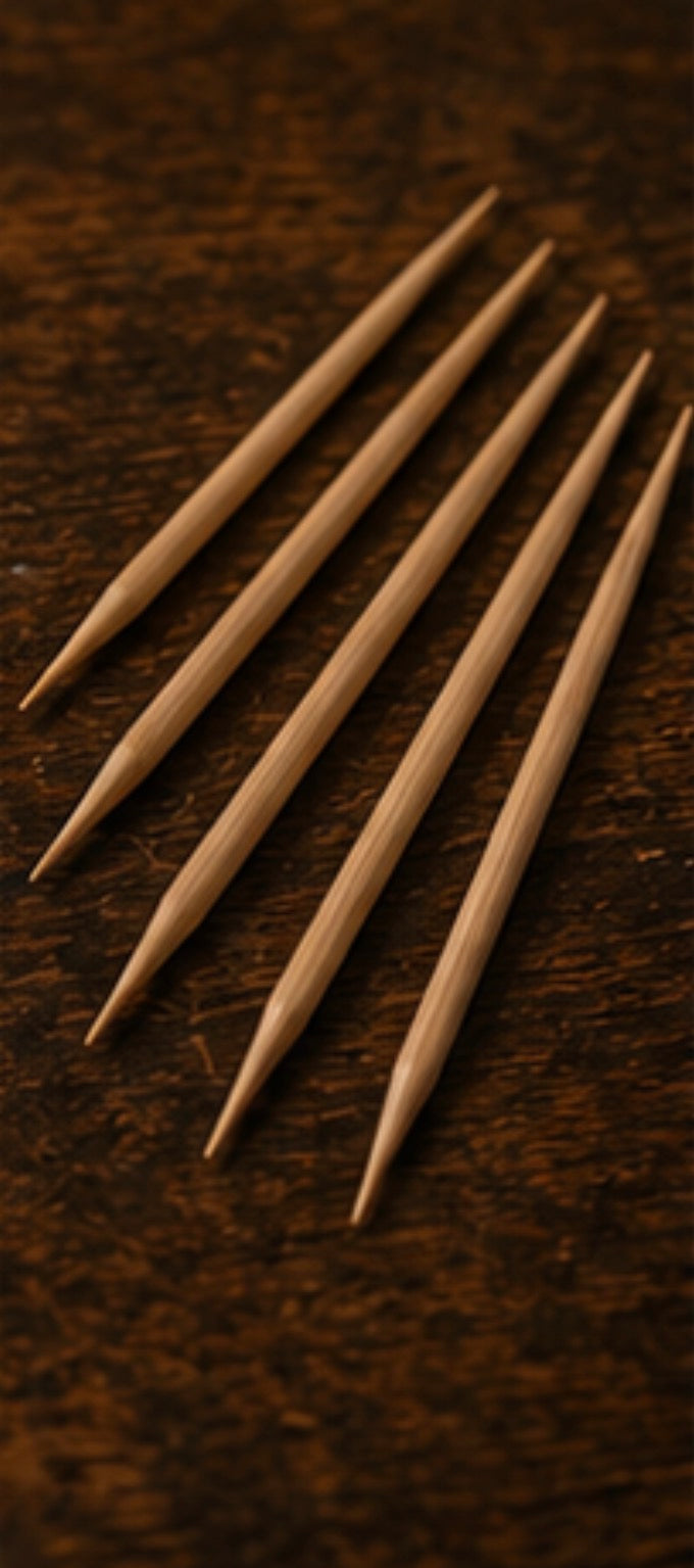 Five wooden Cinder Picks on a dark brown textured surface