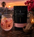 Cinder Picks Pink Sangria package with a glass of pink sangria and lemon slices on a sunset background.