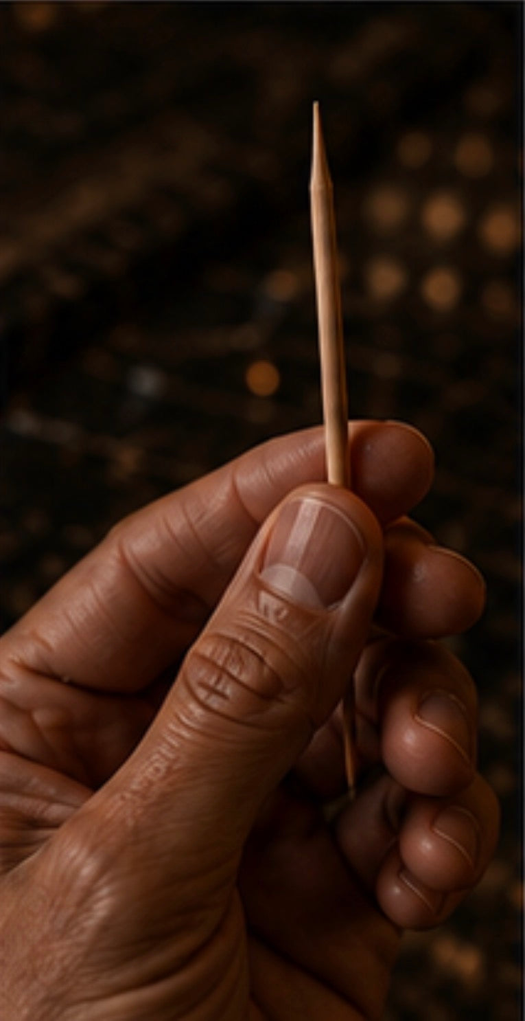 Hand holding a Cinder Pick against a dark background
