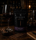 Cinder Picks Pinot Noir packaging with a glass of wine and decanter on a dark background.