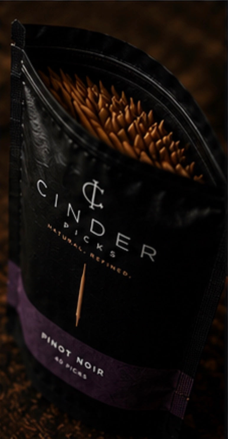 Cinder Picks packaging with brand name and product details on a dark background