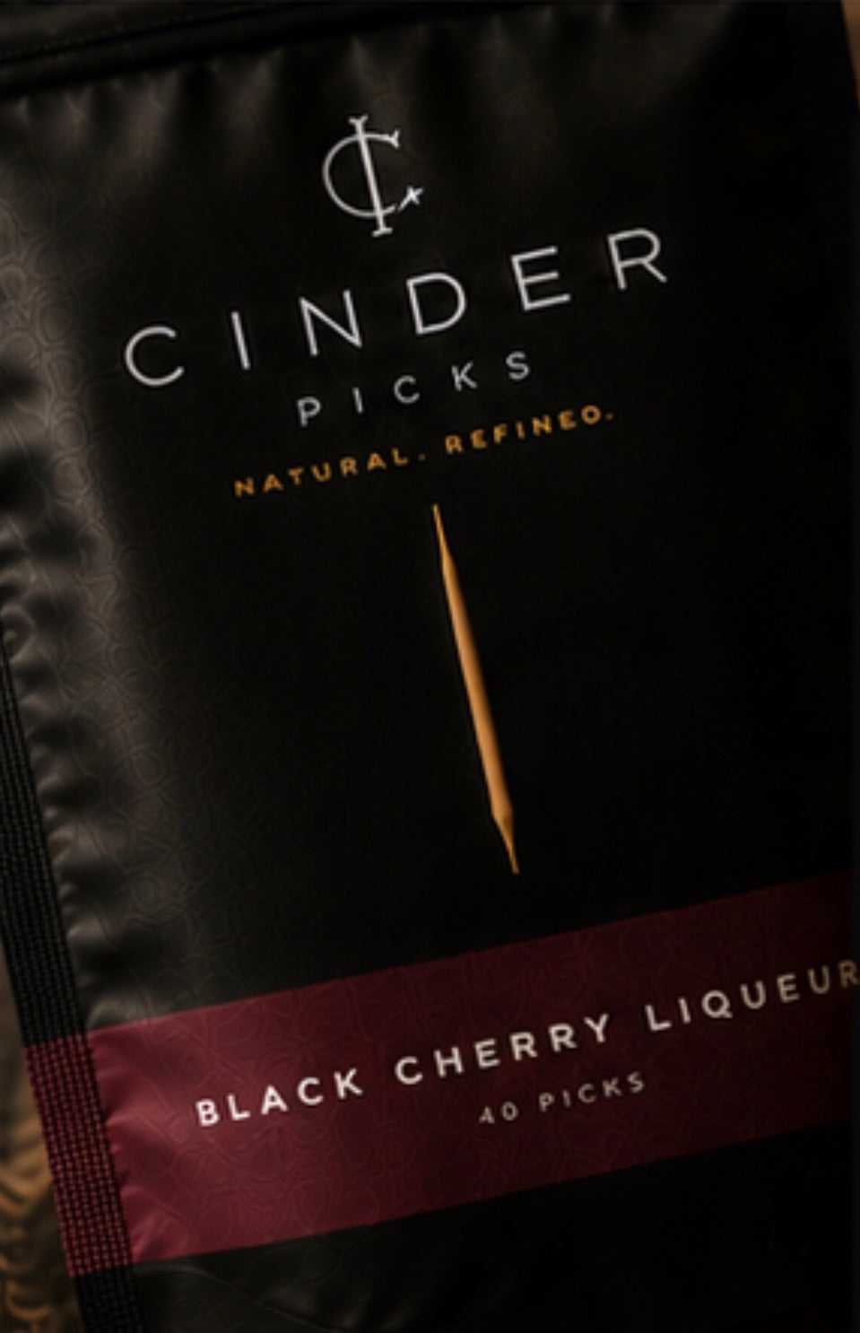Cinder Picks packaging for black cherry liqueur on a dark background