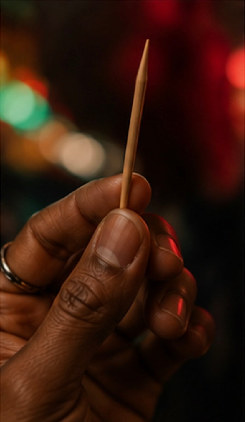 Hand holding a toothpick with a blurred background