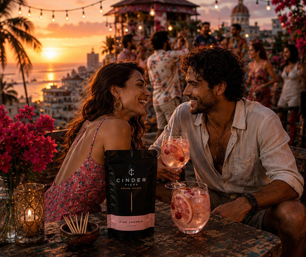 Couple enjoying drinks at a rooftop bar with a sunset view and Cinder Picks Pink Sangria pouch in the foreground